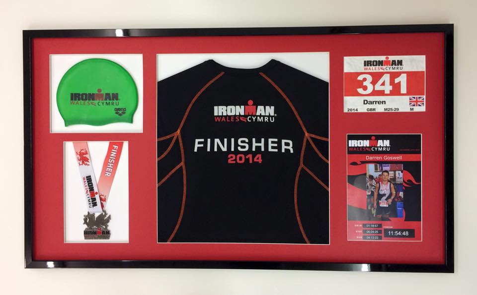 Ironman challenge memorabilia in a black frame with red mount