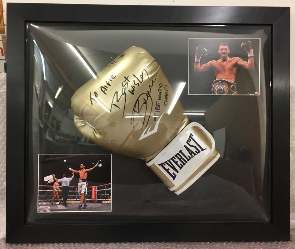 Golden boxing mit in a black frame with two pictures of the boxer in the ring